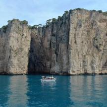 a boat in the water next to a large cliff