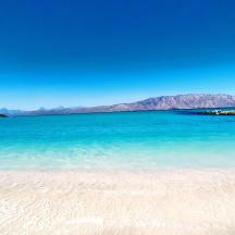 una spiaggia con acqua blu e montagne sullo sfondo