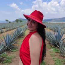 a woman in a red hat standing in a pineapple field