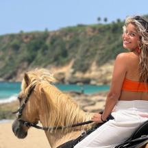 a woman riding a horse on the beach