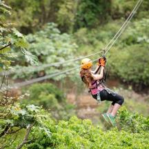 a woman on a zip line in the forest