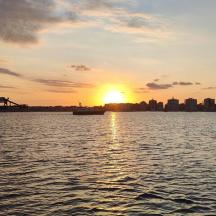 a sunset over a body of water with a city
