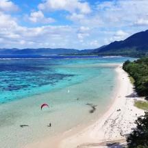a beach with a person parasailing in the water