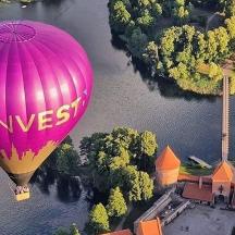 bir nehrin üzerinde uçan pembe bir sıcak hava balonu