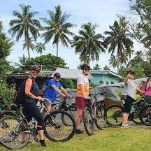 a group of people standing with bikes in the grass