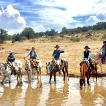 a group of people riding horses in the water