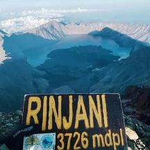 un cartello sulla cima di una montagna con un lago
