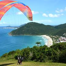 a person flying a kite on a hill near the ocean