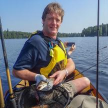 a man sitting in a boat holding a large fish