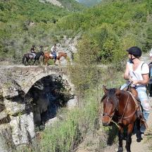 un grup de persones muntant a cavall per un pont