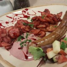 en tallerken med mat med pølse og grønnsaker på et bord