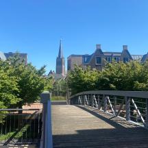 a bridge over a walkway with a city in the background