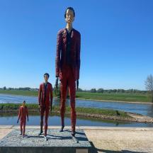 a statue of three men standing next to a river