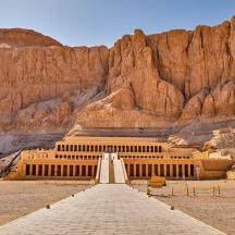 a building in the middle of a desert with a mountain