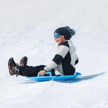 ein kleiner Junge, der mit einem Snowboard einen schneebedeckten Hang hinunterfährt