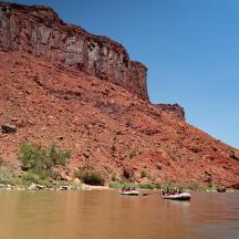 eine Gruppe von Menschen in Kanus auf einem Fluss neben einem Berg