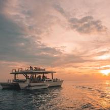 ein Boot im Meer mit einem Sonnenuntergang im Hintergrund