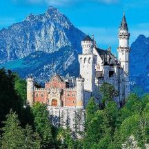 a castle on a hill with mountains in the background