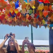 two girls taking pictures with their cell phones in front of a bunch of colorful paper