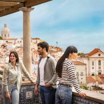 a group of people standing on a ledge looking at a city