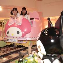 two girls riding on a toy train in a mall