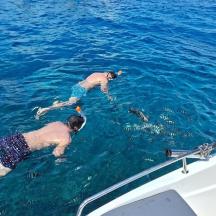 two people swimming in the water next to a boat