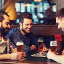 tres homes asseguts a una taula bevent cervesa