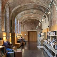 o bibliotecă cu rânduri de rafturi și oameni așezați pe scaune