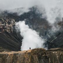 a person standing on top of a mountain with smoke