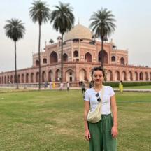 a woman standing in a field in front of a building