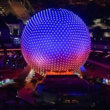 a large blue sphere is lit up at night