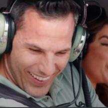 a man wearing headphones with a woman behind him