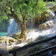 eine Frau, die auf einem Zaun vor einem Wasserfall sitzt