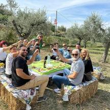 un grup de persones assegudes al voltant d'una taula sobre bales de palla