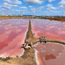 a large body of pink water with a sand castle