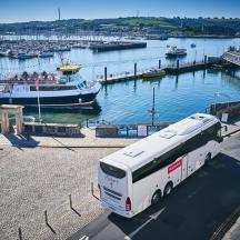 a bus parked in front of a marina with boats