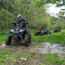 a group of people riding atvs on a muddy trail