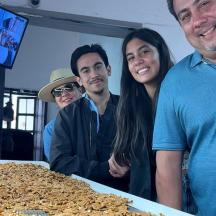 un grup de persones dretes al costat d'una taula de menjar