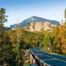 una carretera buida amb arbres i muntanyes al fons