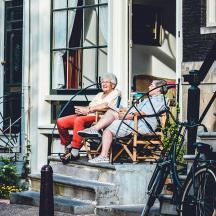 two women sitting on a bench outside of a building