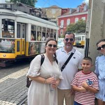 a family posing for a picture in front of a tram