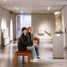 two people sitting on a bench in an art museum