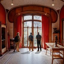 three people standing in a living room looking out the window