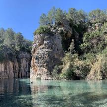 a body of water next to a rocky mountain