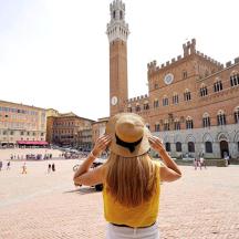 a woman wearing a hat looking at a clock tower