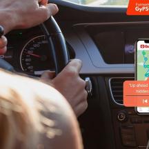 a person driving a car with a cell phone on the dashboard