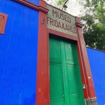 Un edificio colorido con una puerta verde y un árbol