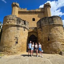 three people standing in front of a castle
