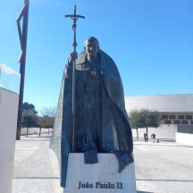eine Statue eines Mannes mit einem Kreuz vor einem Gebäude