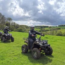 zwei Personen fahren mit Quads auf einem Feld mit